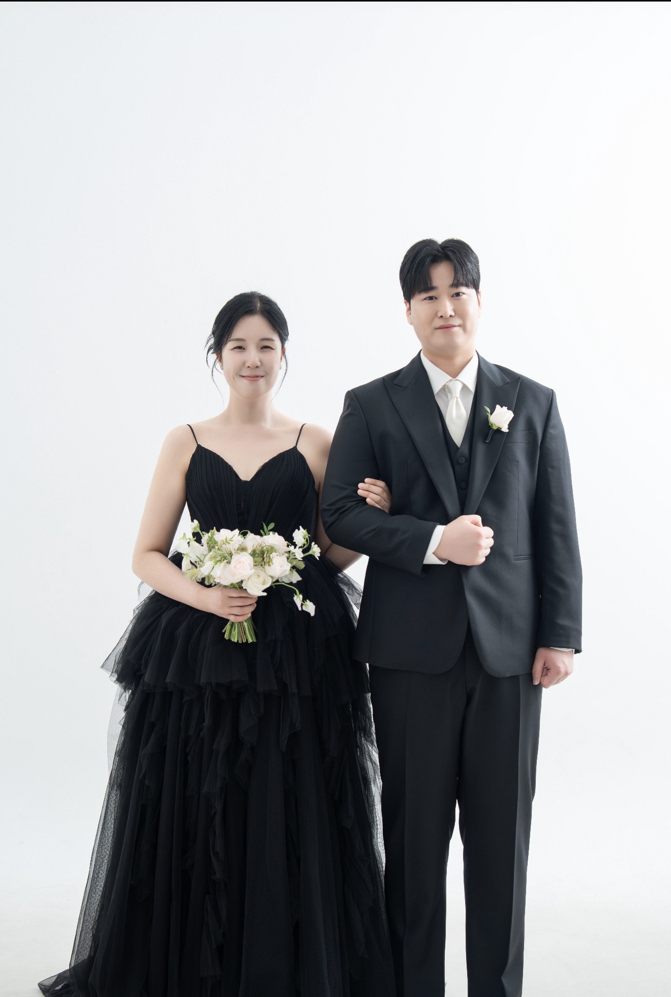 검은 드레스와 정장을 입고 팔짱을 낀 예비부부